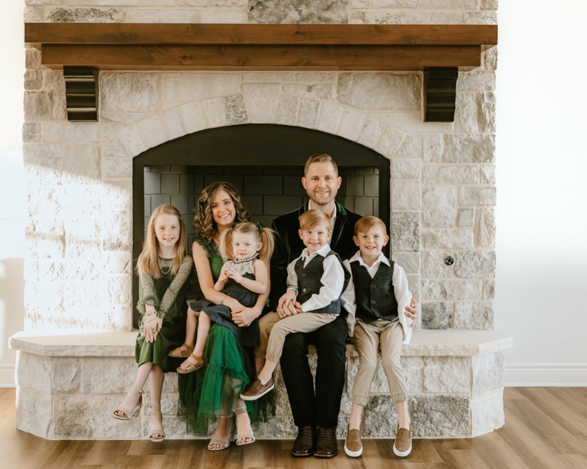 Kids dental professional wearing plaid collared shirt and sportscoat with arm around wife with long, wavy hair.